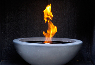 a firebowl within a fireplace creates the focal point in this garden design in caterham, surrey