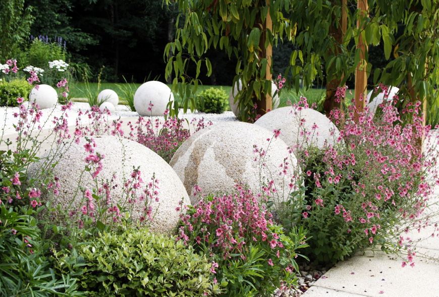 yellow granite sculptural balls contrast with pink and purple planting scheme in this garden design in crouch, kent